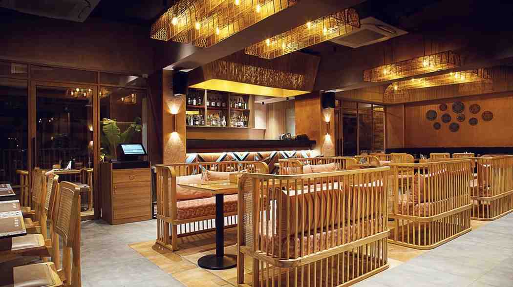 Warm-lit lounge with bold woven rattan booth dividers and patterned lighting fixtures